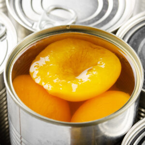 Canned peaches in just opened tin can. Non-perishable food